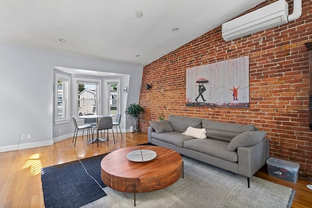 living room featuring lofted ceiling, light hardwood / wood-style flooring, brick wall, and an AC wall unit