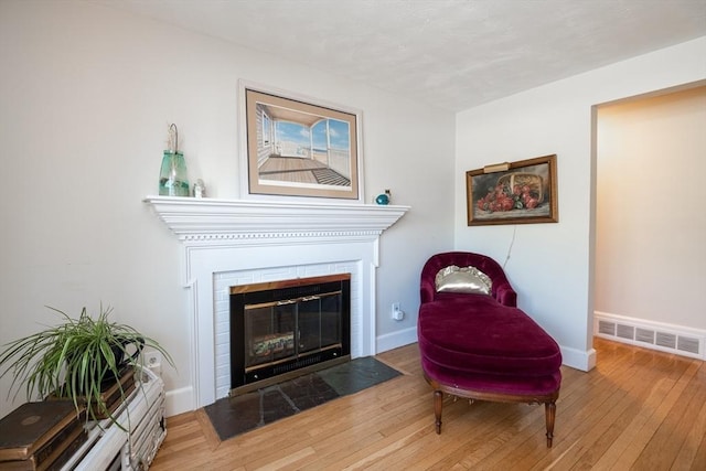 sitting room with baseboards, a fireplace, hardwood / wood-style floors, and visible vents