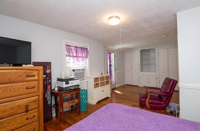 bedroom featuring cooling unit, two closets, and wood finished floors