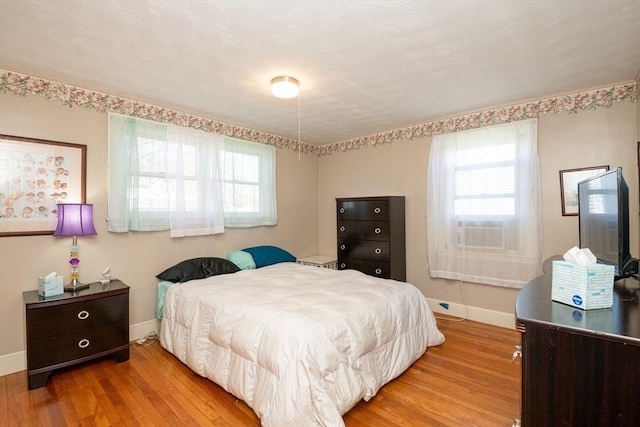 bedroom with baseboards, wood finished floors, and cooling unit