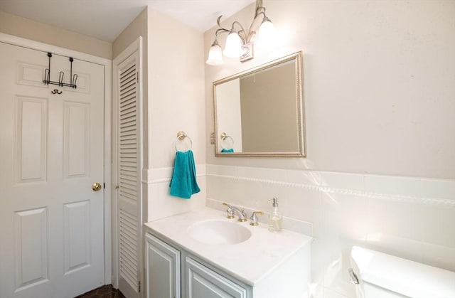 bathroom featuring vanity, a wainscoted wall, and toilet