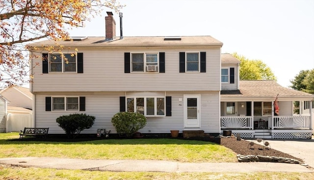 colonial-style house with a porch, a front lawn, and a chimney