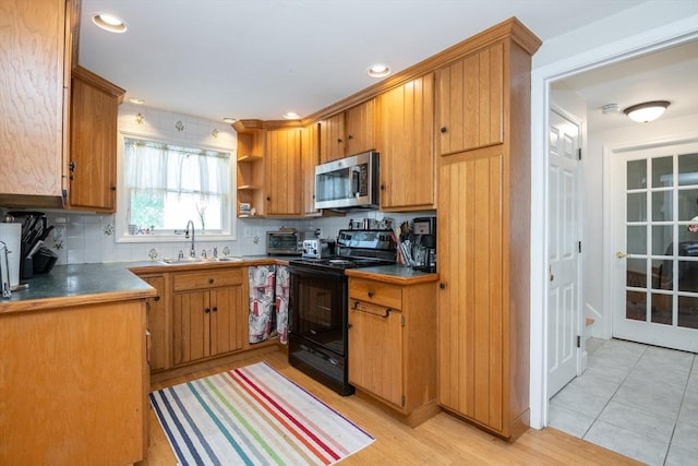kitchen featuring dark countertops, a sink, stainless steel microwave, decorative backsplash, and black range with electric cooktop
