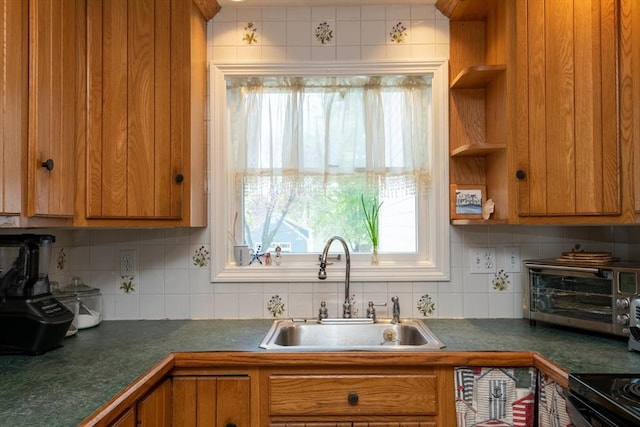 kitchen featuring a sink, dark countertops, brown cabinetry, and a healthy amount of sunlight