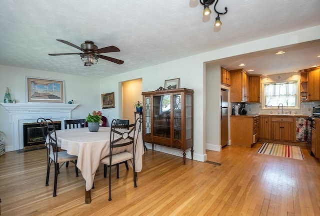 dining room with light wood-style flooring, a ceiling fan, baseboards, a fireplace with flush hearth, and recessed lighting