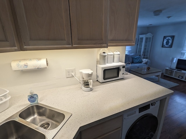 kitchen featuring washer / dryer, sink, and dark hardwood / wood-style flooring