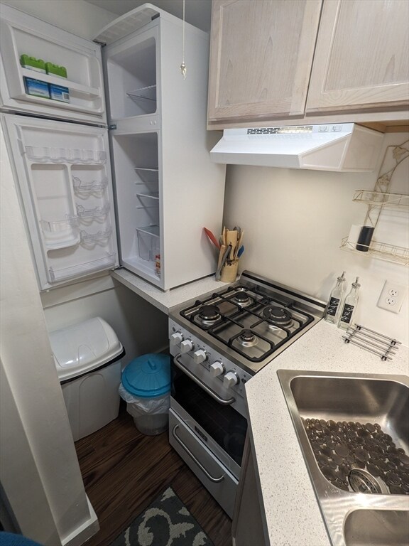 kitchen with light brown cabinets, custom range hood, range with two ovens, dark wood-type flooring, and sink