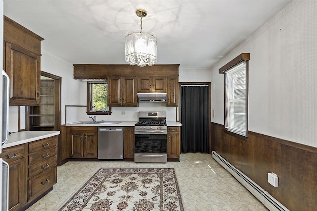 kitchen featuring stainless steel appliances, a baseboard radiator, under cabinet range hood, light countertops, and a wainscoted wall