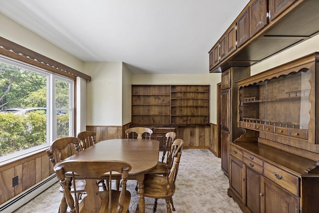 dining area with wainscoting, wooden walls, light carpet, and baseboard heating