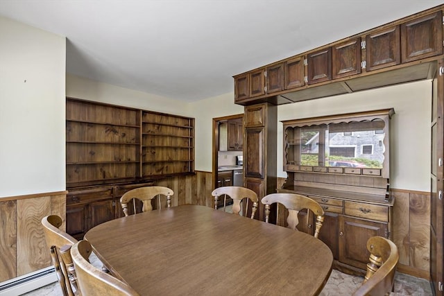 dining space featuring a wainscoted wall, wooden walls, and a baseboard radiator