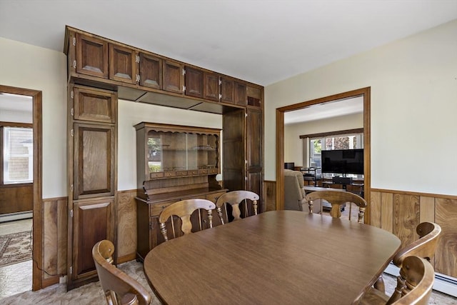 dining area with wainscoting, wood walls, and baseboard heating