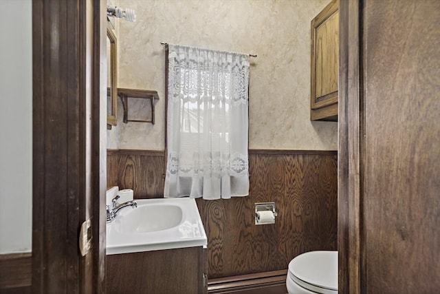 bathroom featuring a baseboard heating unit, toilet, a wainscoted wall, and vanity