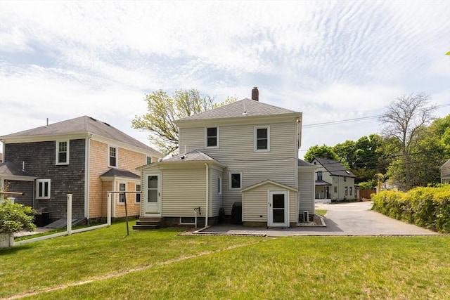 rear view of house with a chimney, a lawn, a patio, and entry steps