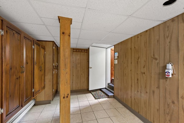 entrance foyer with baseboard heating, wood walls, a paneled ceiling, baseboards, and light tile patterned floors