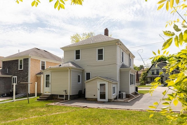 rear view of house with a patio area, a chimney, entry steps, and a lawn