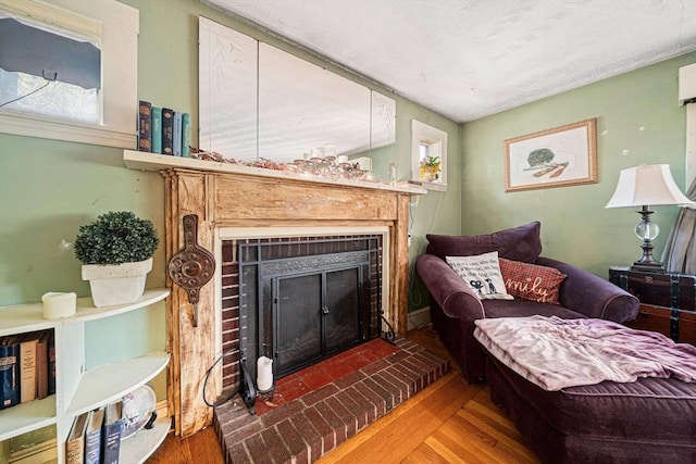 living area featuring a brick fireplace and wood finished floors