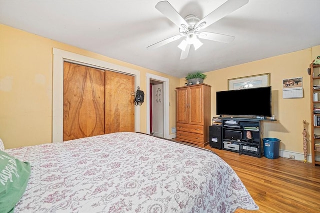 bedroom with baseboards, ceiling fan, wood finished floors, and a closet