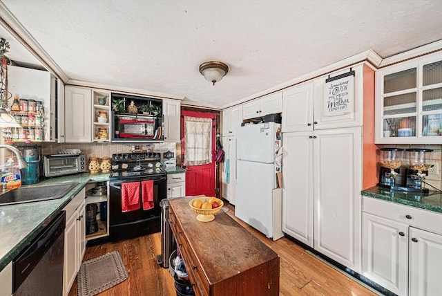 kitchen featuring stainless steel dishwasher, freestanding refrigerator, dark countertops, black electric range, and a sink