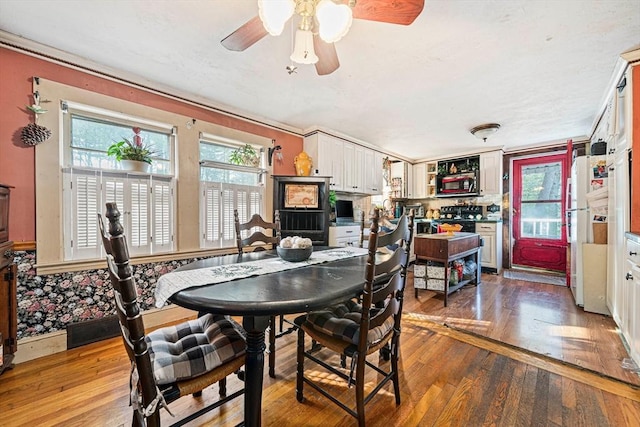 dining area with wood-type flooring, ceiling fan, and crown molding