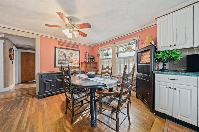 dining space with baseboards, ceiling fan, light wood-type flooring, and a textured ceiling