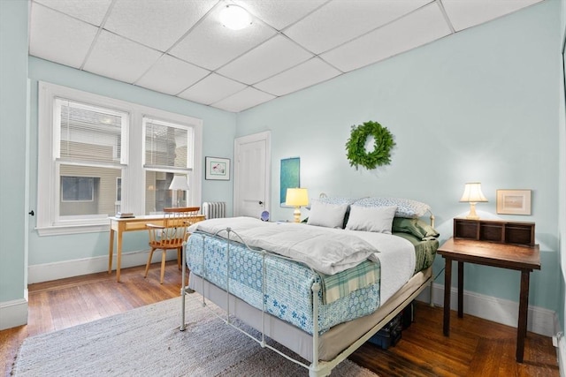 bedroom with a drop ceiling and hardwood / wood-style floors