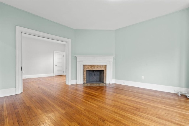 unfurnished living room featuring light hardwood / wood-style flooring and a brick fireplace