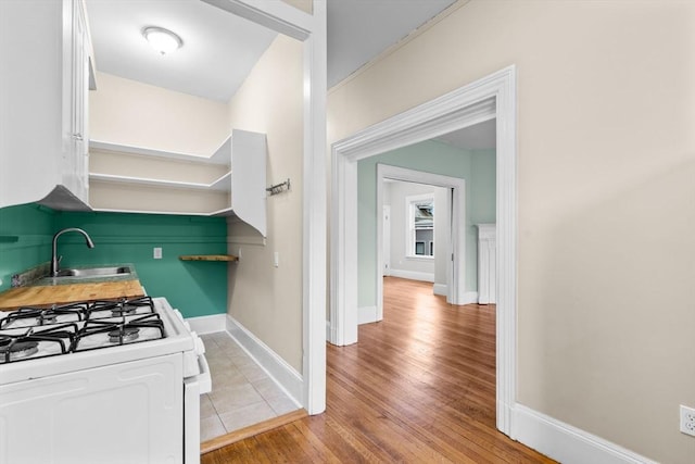 kitchen featuring white cabinets, white gas stove, sink, and light hardwood / wood-style flooring