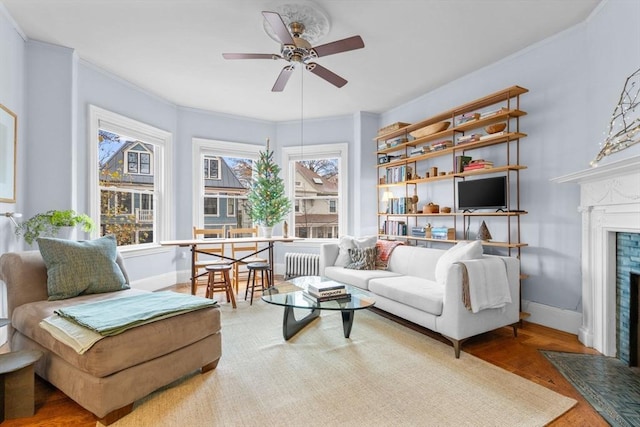 living room featuring hardwood / wood-style floors, radiator heating unit, ceiling fan, and crown molding