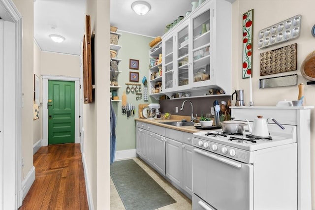 kitchen with white gas range, white cabinetry, sink, and dark hardwood / wood-style floors