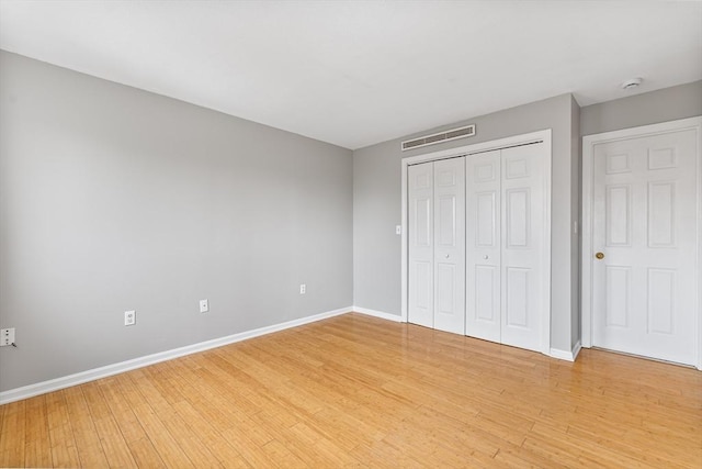 unfurnished bedroom featuring a closet, light wood-type flooring, visible vents, and baseboards