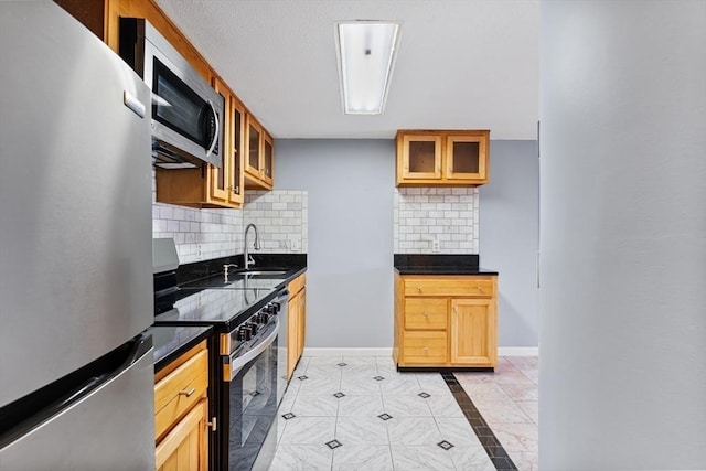 kitchen featuring backsplash, appliances with stainless steel finishes, glass insert cabinets, and a sink