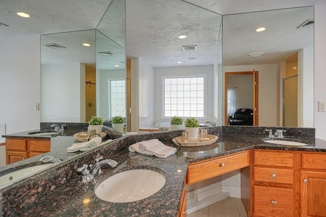 bathroom with walk in shower, vanity, and tile patterned flooring