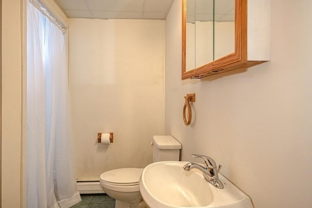 bathroom featuring a paneled ceiling, sink, tile patterned flooring, baseboard heating, and toilet