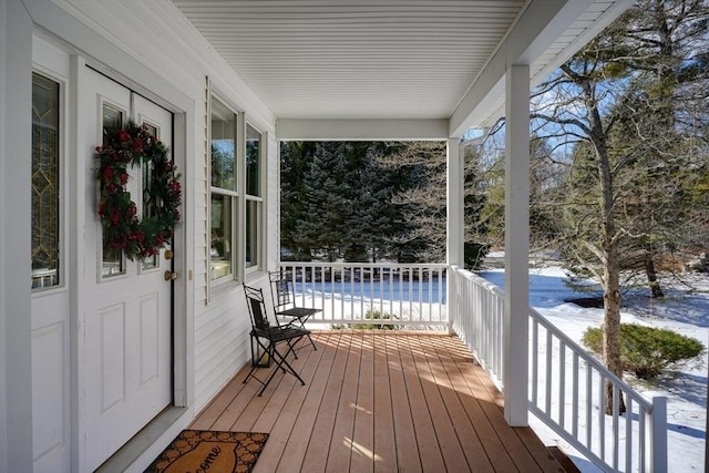 snow covered deck featuring a porch