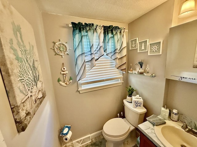 half bath with a textured ceiling, toilet, and vanity