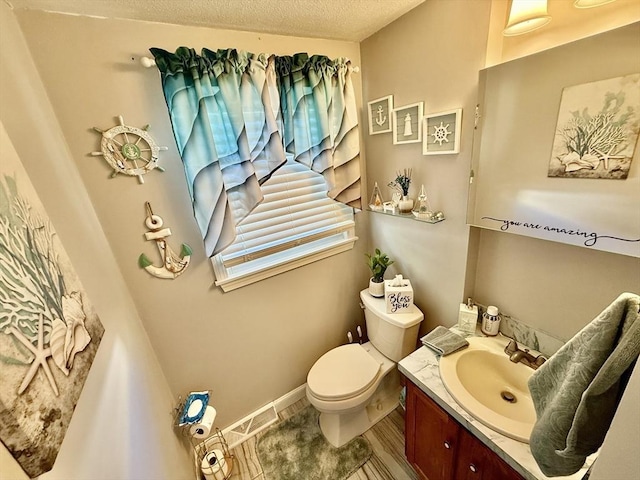 bathroom with vanity, toilet, and a textured ceiling
