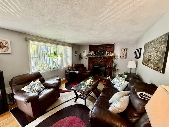 living area with wood finished floors, a textured ceiling, and a brick fireplace