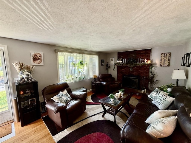 living room featuring a textured ceiling, a fireplace, and light wood-style flooring