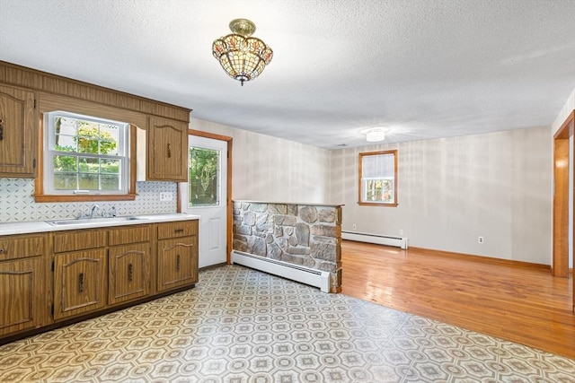 97 Marshall St, Revere, MA 02151 - kitchen with baseboard heating, brown cabinetry, light countertops, and a textured ceiling