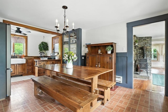 114 Center St, Carver, MA 02330 - dining room with brick patterned floors, ceiling fan, baseboard heating, and a wood stove