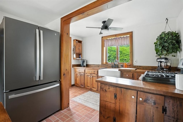 114 Center St, Carver, MA 02330 - kitchen featuring freestanding refrigerator, brick patterned floors, brown cabinets, range with gas stovetop, and ceiling fan