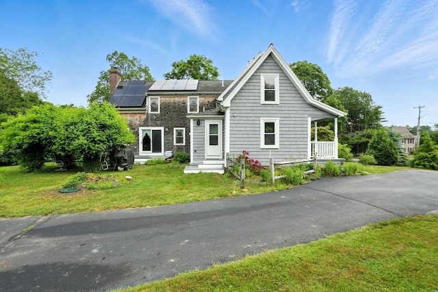 114 Center St, Carver, MA 02330 - view of front of property featuring entry steps, a front lawn, roof mounted solar panels, and a chimney