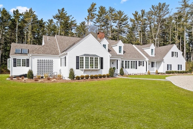 cape cod house featuring a shingled roof and a front lawn