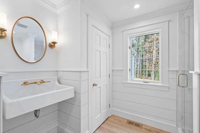 bathroom with visible vents, a shower stall, ornamental molding, wood finished floors, and a sink