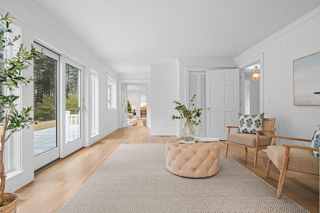 sitting room featuring light wood-type flooring, baseboards, ornamental molding, and french doors