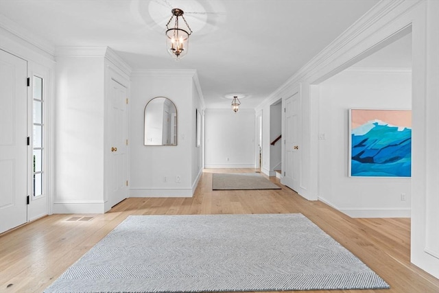 foyer entrance featuring baseboards, a chandelier, stairs, ornamental molding, and wood finished floors