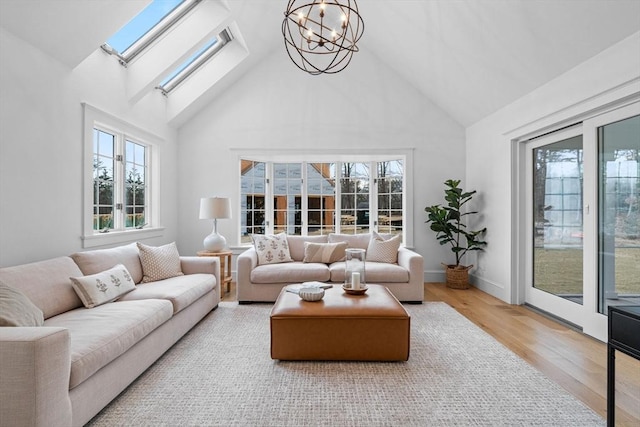 living area with a chandelier, a skylight, high vaulted ceiling, and wood finished floors