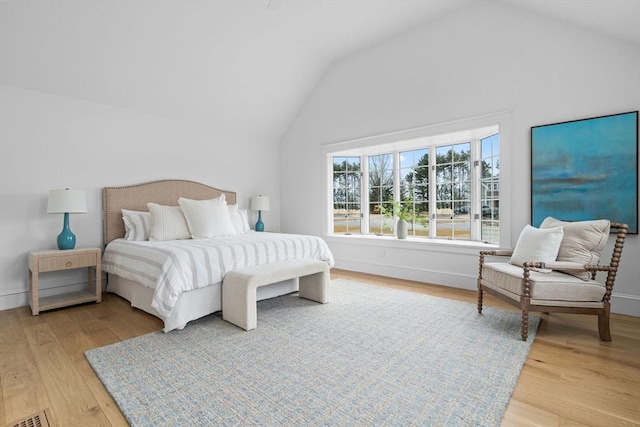 bedroom with baseboards, light wood-type flooring, and lofted ceiling