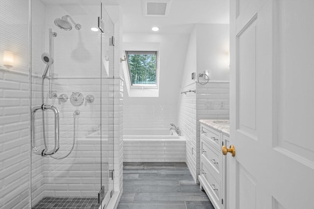 bathroom with visible vents, a garden tub, wood finished floors, a shower stall, and vanity