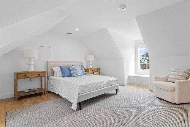 bedroom with vaulted ceiling, baseboards, and wood finished floors